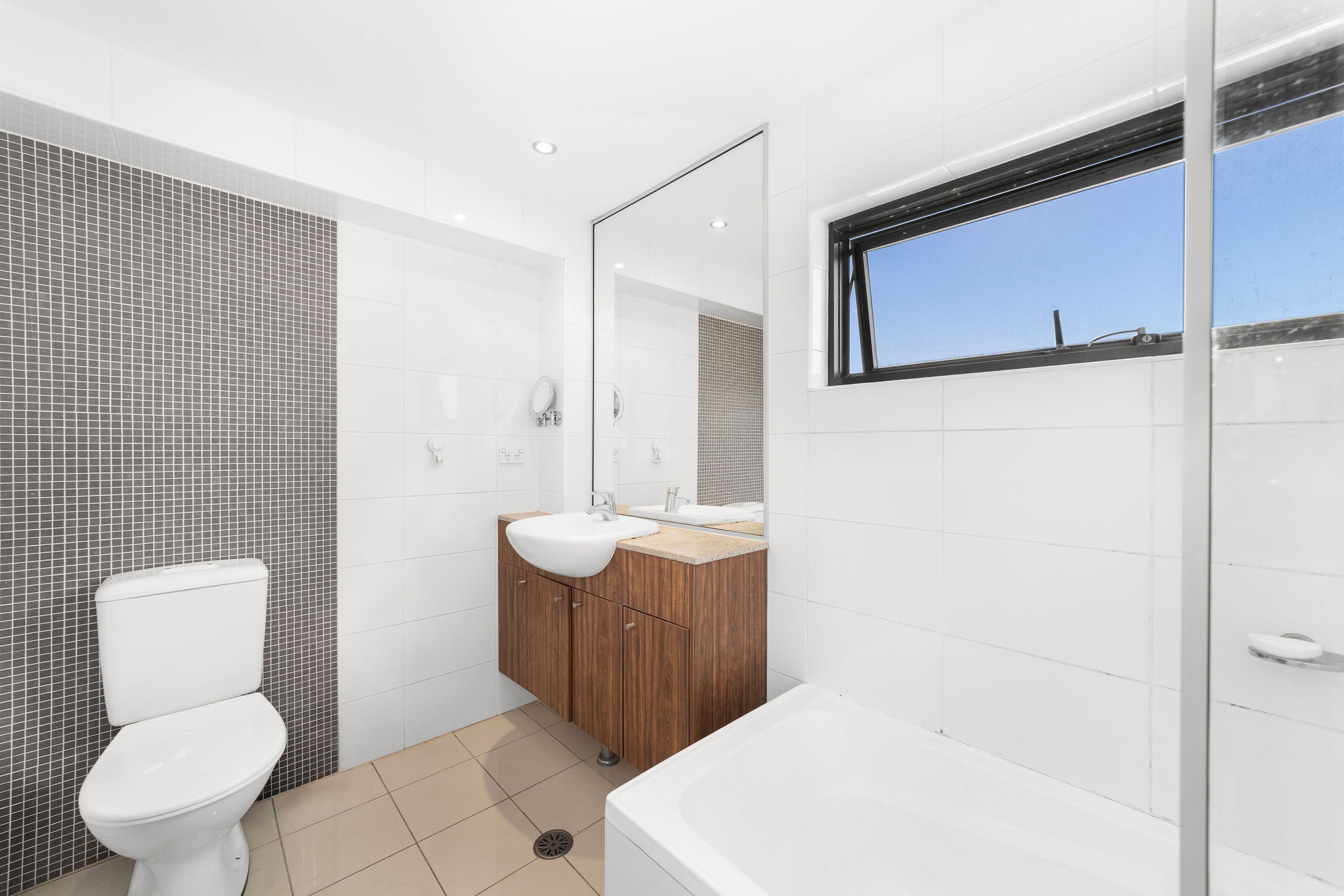 Stylish bathroom featuring modern fixtures, wooden cabinetry, and a sleek tiled wall, highlighting a furnished loft's contemporary design in Alexandria.