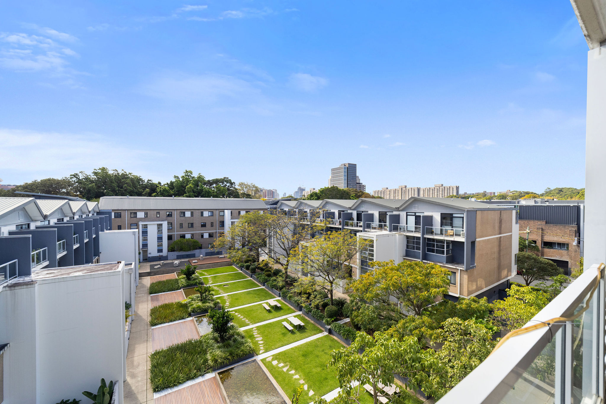 Stylish loft apartment view overlooking tranquil communal gardens in Alexandria, featuring landscaped greenery, seating areas, and modern architecture.