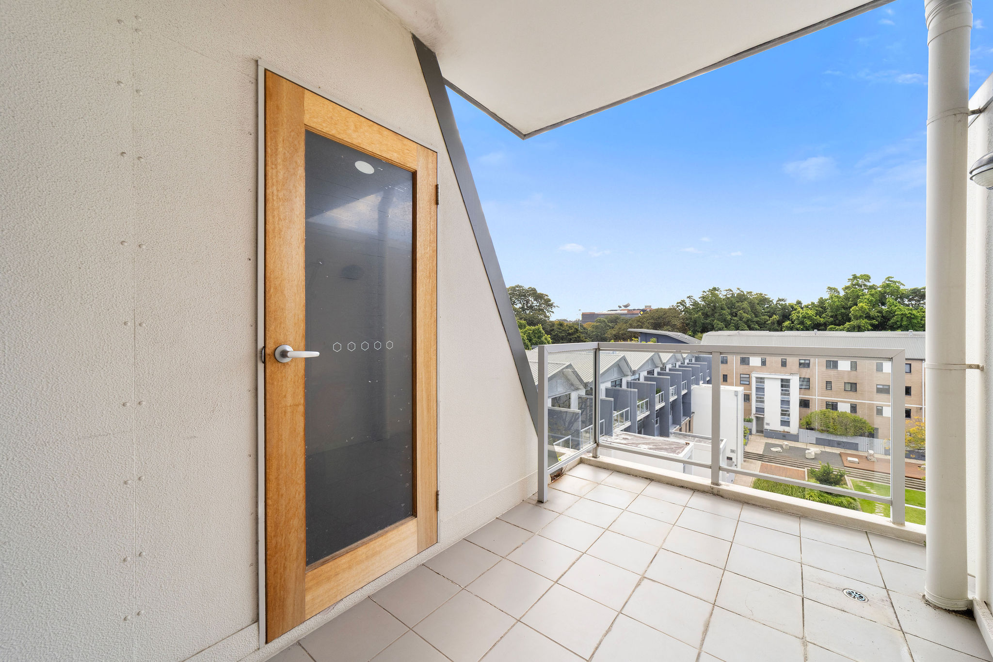 Stylish balcony view from a furnished loft in Alexandria, featuring a wooden door and a serene garden outlook.