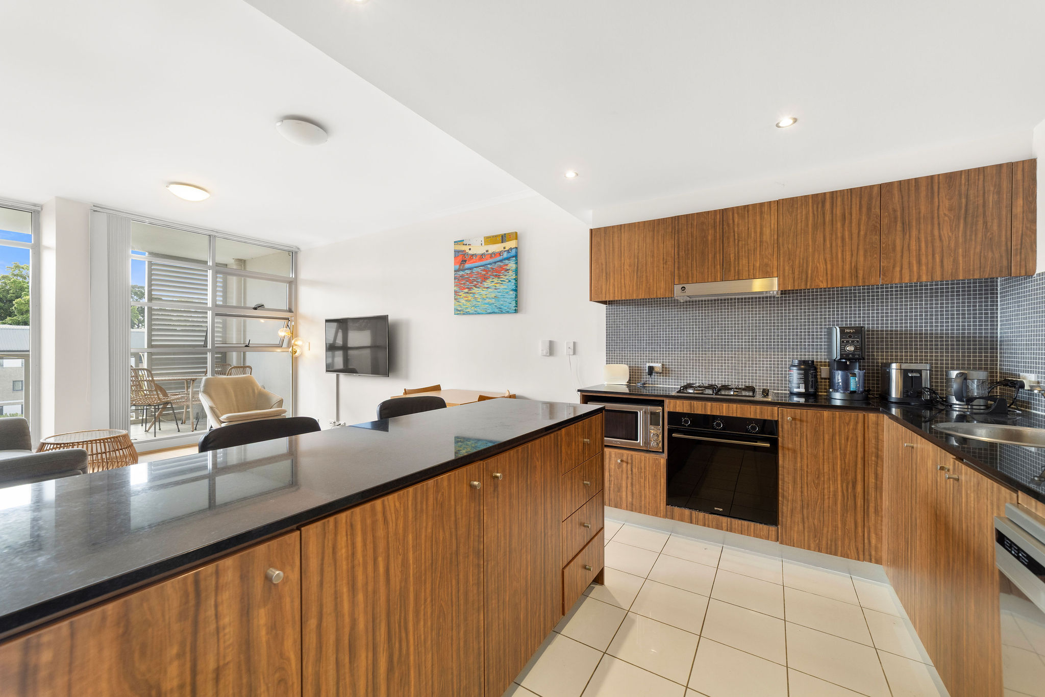 Stylish furnished loft kitchen with wooden cabinetry, modern appliances, and natural light, overlooking tranquil gardens in Alexandria.